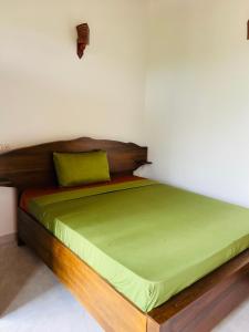 a bed with a wooden frame and green sheets at Thilaka villa in Induruwa