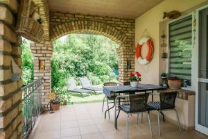 a patio with an archway and a table and chairs at Toldi68 Apartmanház in Keszthely
