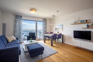 sala de estar con sofá azul y mesa con vistas en Reeders Nest by Seeblick Ferien, en Olpenitz