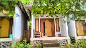 a house with a wooden door and a chair in front at Diki Bungalows in Kuta Lombok