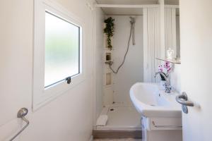 a white bathroom with a sink and a window at Club del Sole Riccione Easy Camping Village in Riccione +30 photos
