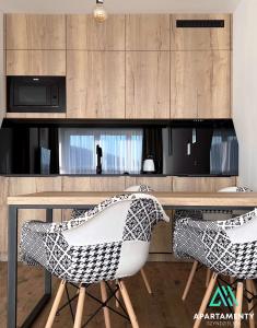 eine Küche mit einem Tisch mit 2 Stühlen und einer Mikrowelle in der Unterkunft APARTAMENTY SZYNDZIELNIA RODZINNE - 2 SYPIALNIE & BALKON & GÓRY & Parking - TWOJA BAZA WYPADOWA NA SZLAKI i W GÓRY - FAMILY SPACE & BASE in Bielsko-Biała