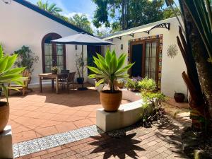 a patio with potted plants and an umbrella at Beach Bliss - Private Suite, Tropical Tranquility, 3 mins walk to beach in Suffolk Park