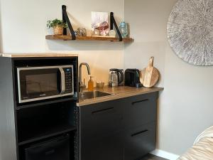 a kitchen with a microwave and a sink at Hello Noordwijk - Studio Pietheinplein 1 in Noordwijk aan Zee