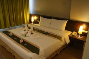 ein Hotelzimmer mit einem großen Bett mit Blumen darauf in der Unterkunft Aloha Hatyai Hotel in Hat Yai