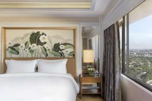 马尼拉Dusit Thani Manila的一间卧室,里面有一张床和一扇大窗户。