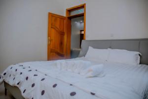 un letto bianco in una stanza con porta in legno di Mama's Favourite ltd a Kigali