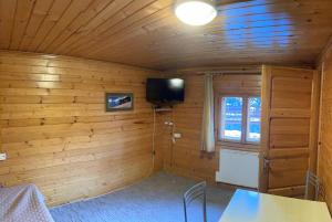a room with a wooden wall with a television in it at Chata pod Pustą in Wierchomla Mała