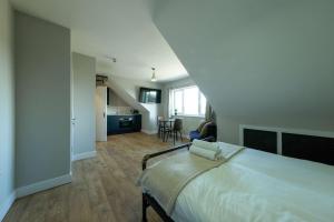 a bedroom with a large white bed and a kitchen at The Willow Apartments in Bristol