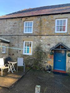 a brick house with a blue door and a table at Low Houses Hadrians Wall in Stagshaw Bank