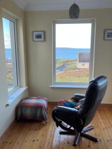 uma cadeira preta sentada em uma sala com duas janelas em Sea views in Dugort em Achill Island
