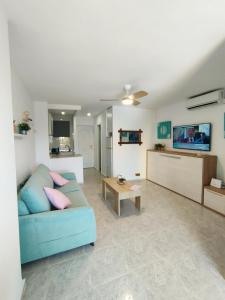 a living room with a blue couch and a tv at Apartamento Aguila in Benalmádena +18 photos