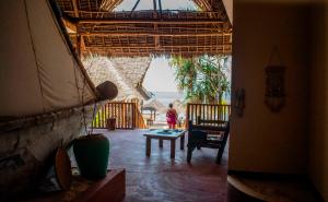 a woman standing in a living room with a view of the ocean at Pazuri kendwa Beach Hotel in Nungwi