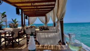 a restaurant on the beach with white chairs and the ocean at Queen Ekaterina II in Vlorë