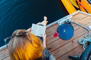a woman reading a book on a boat at Abenteuer Flusslandschaft - Hausboot fest vertäut in Mecklenburg-Vorpommern in Anklam +3 photos