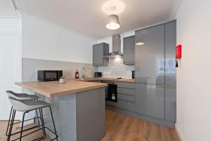 a kitchen with white cabinets and a counter and stool at Leeds City Centre - Sleeps 5 - Free Parking in Leeds +15 photos