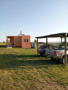 ein Haus und zwei Autos auf einem Feld geparkt in der Unterkunft Los Espinillos in Villa Yacanto + 6 Fotos