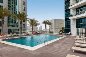 a swimming pool with palm trees and buildings at New Renovated Modern 1 Br Dubai Marina in Dubai