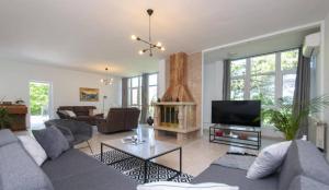 a living room with a couch and a tv at Nature View Spacious Five Bedroom Villa, Pool in Zadvarje