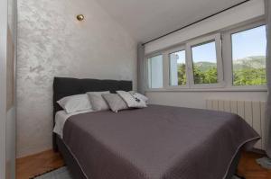 a bedroom with a large bed with two windows at Nature View Spacious Five Bedroom Villa, Pool in Zadvarje +34 photos
