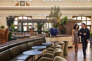 a man and a woman walking through a lobby at The Crawford Hotel in Denver