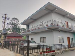 a white house with a car parked in front of it at Cozy Corner Homestay in Madikeri
