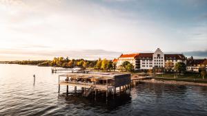 ein Dock auf einem Wasserkörper mit einem Gebäude in der Unterkunft Seehotel am Kaiserstrand in Lochau