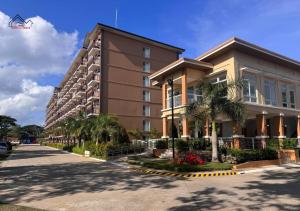 a large building with palm trees in front of it at 2BedRoom Staycation Near Airport with a Balcony, FREE Pool, Gym & Parking- B2 3MoonstoneB in Puerto Princesa City