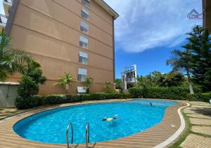a person swimming in a swimming pool next to a building at 2BedRoom Staycation Near Airport with a Balcony, FREE Pool, Gym & Parking- B2 3MoonstoneB in Puerto Princesa City
