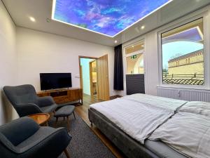a bedroom with a bed and two chairs and a tv at Licht Loft in Itzehoe