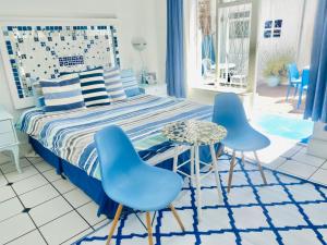 a bedroom with a bed and two blue chairs at A Heavenly View in Muizenberg +134 photos