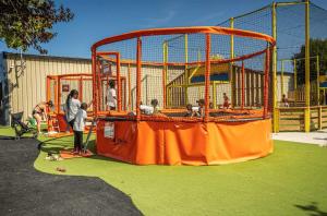 a woman standing in front of a batting cage on a playground at ZEcamping familial dog friendly familial parc aquatique in Olonne-sur-Mer