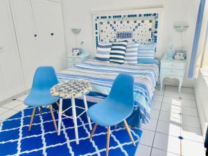 a bedroom with two blue chairs and a bed at A Heavenly View in Muizenberg