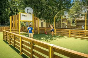 a couple of people playing basketball on a playground at ZEcamping familial avec parc aquatique - chiens acceptés in Saint-Jean-dʼOrbetiers