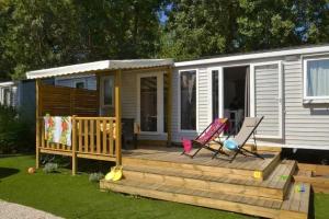 a tiny house with a deck and two chairs on it at ZEcamping familial espace aquatique pet friendly in Argelès-sur-Mer