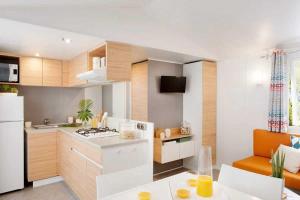 a kitchen with a stove and a white refrigerator at ZEcamping familial espace aquatique pet friendly in Argelès-sur-Mer