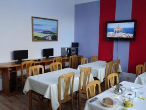 uma sala de jantar com mesas e uma televisão na parede em Tsolmon's Serviced Apartments em Ulan Bator