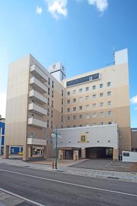 un grand bâtiment sur le côté d'une rue dans l'établissement Hotel Sunroute Goshogawara, à Goshogawara