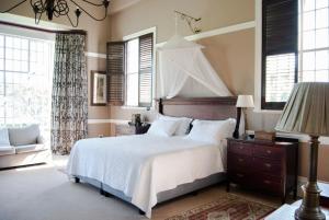 a bedroom with a bed and a lamp and windows at Barnside Guest House in Pietermaritzburg +63 photos