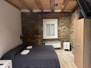 a bedroom with a bed in a stone wall at Hostal Rusó SC in Llivia