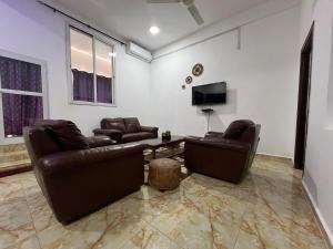 a living room with two leather couches and a tv at One Bedroom Apartment SS5-MARIAM in Kololi +16 photos