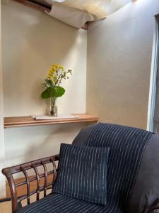 a room with a couch and a vase of flowers on a shelf at 檸檬草ー奄美の自然の香る宿ー in Amami
