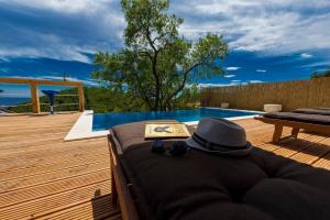 a hat and a book on a bed next to a pool at Calming Area Villa with Infinity Pool in Babino Polje