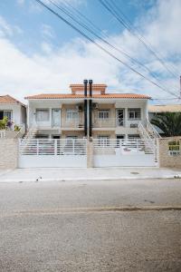 a house with a white fence in front of a street at Residencial Mizinho in Florianópolis