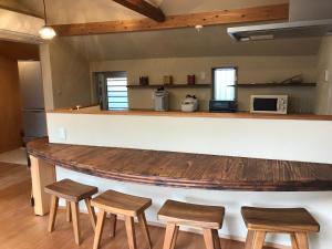 a kitchen with a bar with four stools at 檸檬草ー奄美の自然の香る宿ー in Amami
