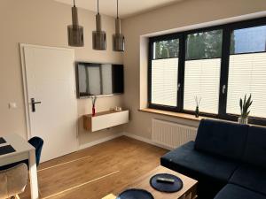 a living room with a black couch and two windows at Apartamenty Na Krasnym in Supraśl