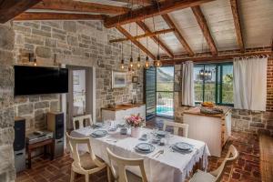 una sala da pranzo con tavolo e sedie bianchi di Countryside Retreat Villa with Pool,Jaccuzi a Klis
