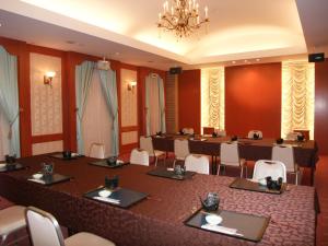 Hotel Sunroute Goshogawara في Goshogawara: قاعة اجتماعات كبيرة مع طاولة وكراسي طويلة