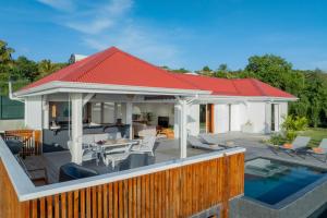 una casa con techo rojo y piscina en Villa Paloma, en Grand-Bourg