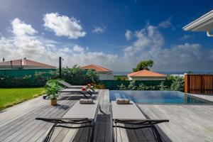 Una terraza con dos sillas y una piscina. en Villa Paloma, en Grand-Bourg